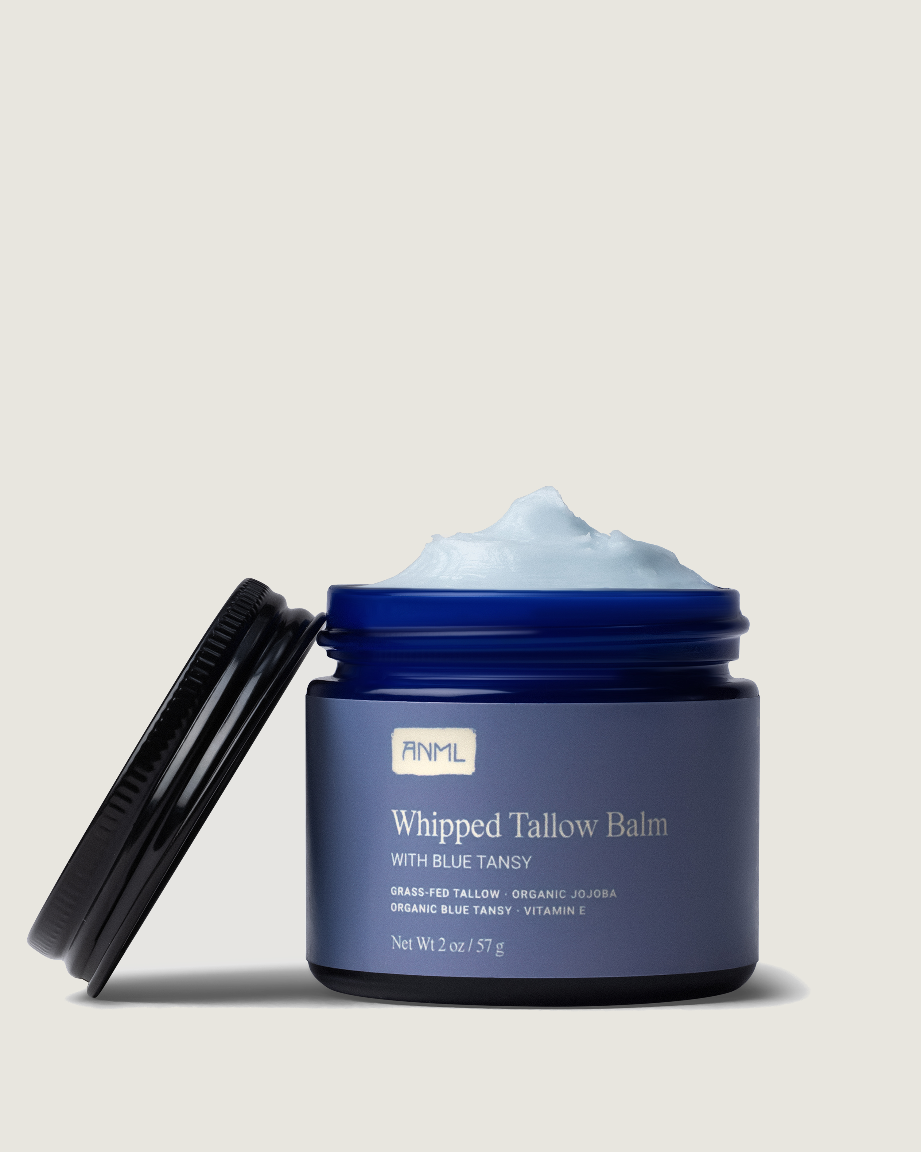 Blue whipped tallow balm jar with open lid on a beige background
