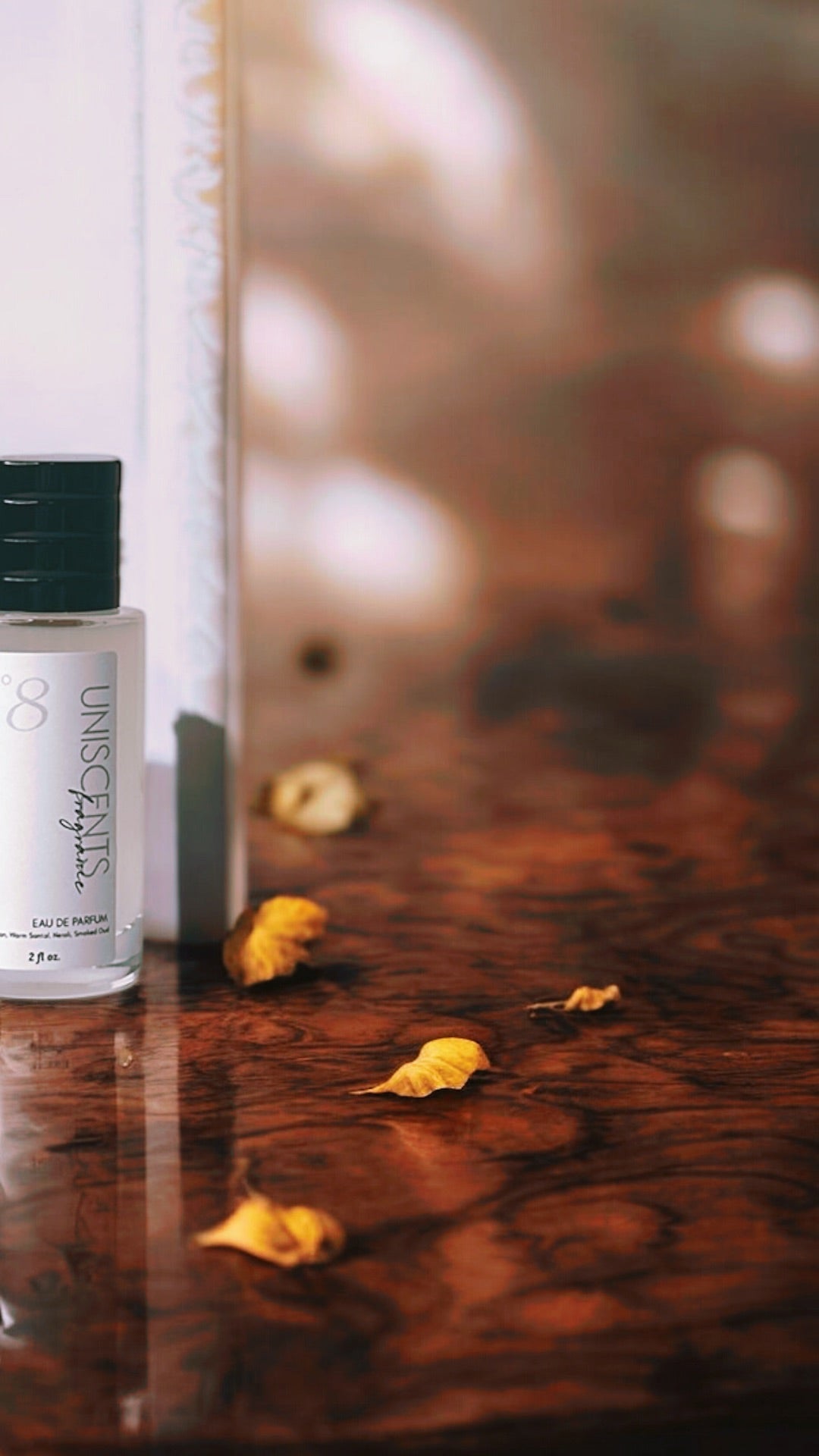 Unscented 8 perfume bottle on a wooden surface with gold leaves.